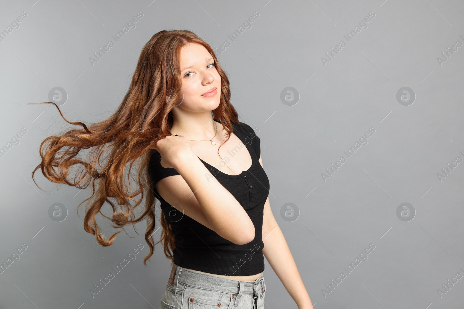 Photo of Teenage girl with long hair on light grey background. Space for text