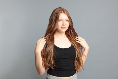 Photo of Teenage girl with healthy long hair on light grey background