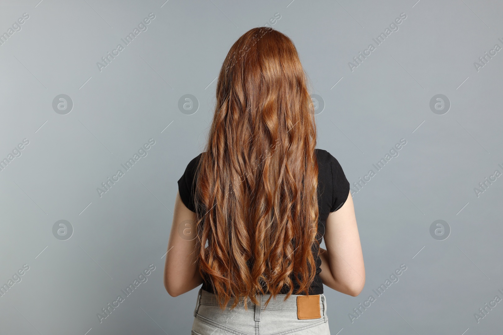 Photo of Teenage girl with healthy long hair on light grey background, back view