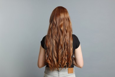 Photo of Teenage girl with healthy long hair on light grey background, back view