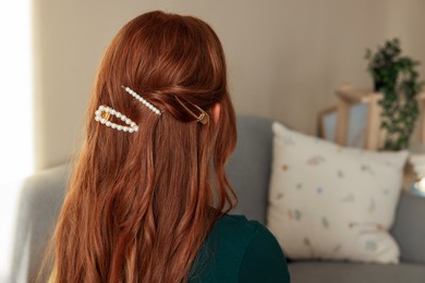 Photo of Teenage girl with stylish hair clips indoors, back view. Space for text