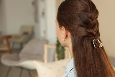 Photo of Teenage girl with stylish hair clip indoors, back view. Space for text