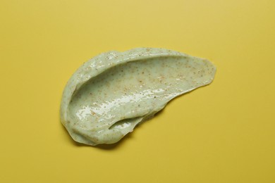 Photo of Smear of body scrub on yellow background, top view