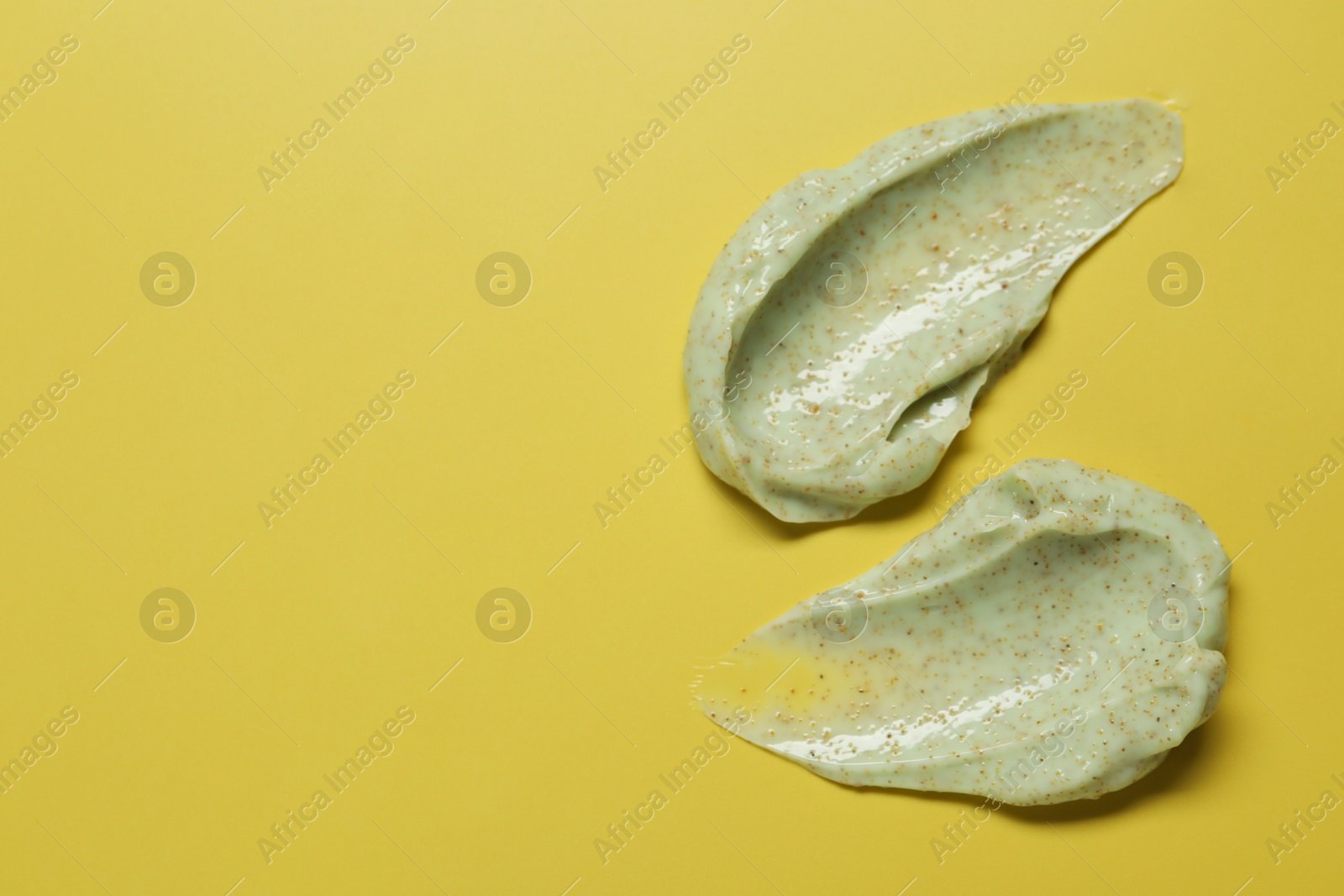 Photo of Smears of body scrub on yellow background, top view. Space for text