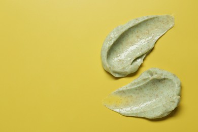 Photo of Smears of body scrub on yellow background, top view. Space for text