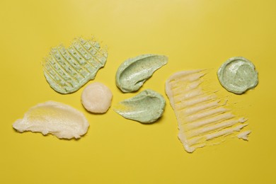 Photo of Samples of different body scrubs on yellow background, top view