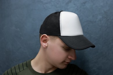 Photo of Man in stylish baseball cap near grey wall. Mockup for design