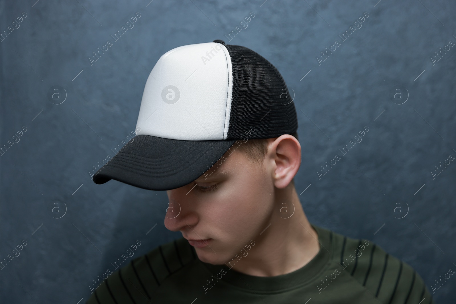 Photo of Man in stylish baseball cap near grey wall. Mockup for design