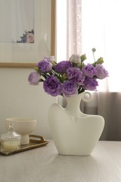 Photo of Stylish vase with beautiful flowers and decor on white wooden table at home