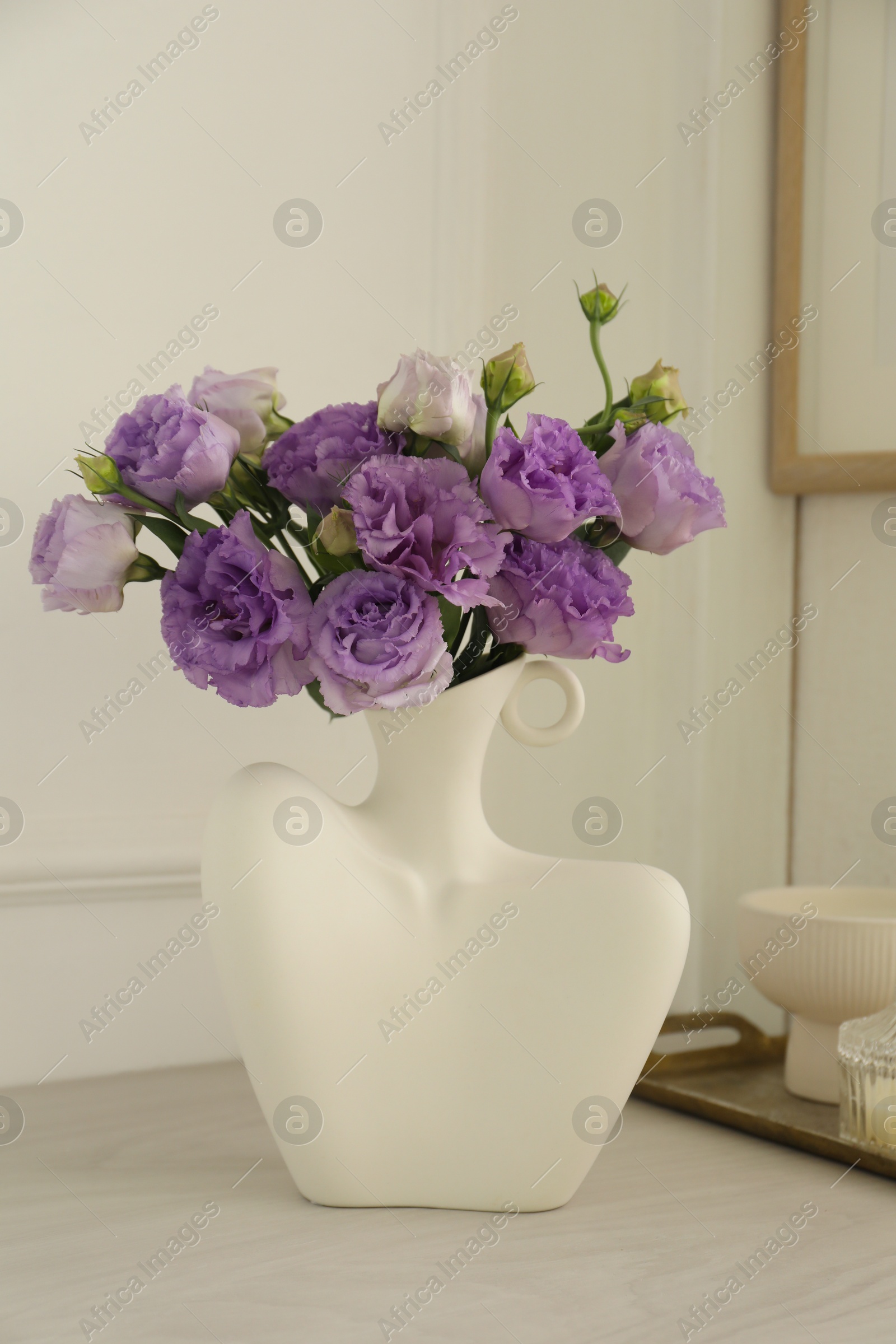 Photo of Stylish vase with beautiful flowers and decor on white wooden table at home