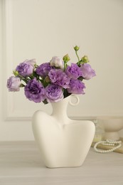 Photo of Stylish vase with beautiful flowers and decor on white wooden table at home