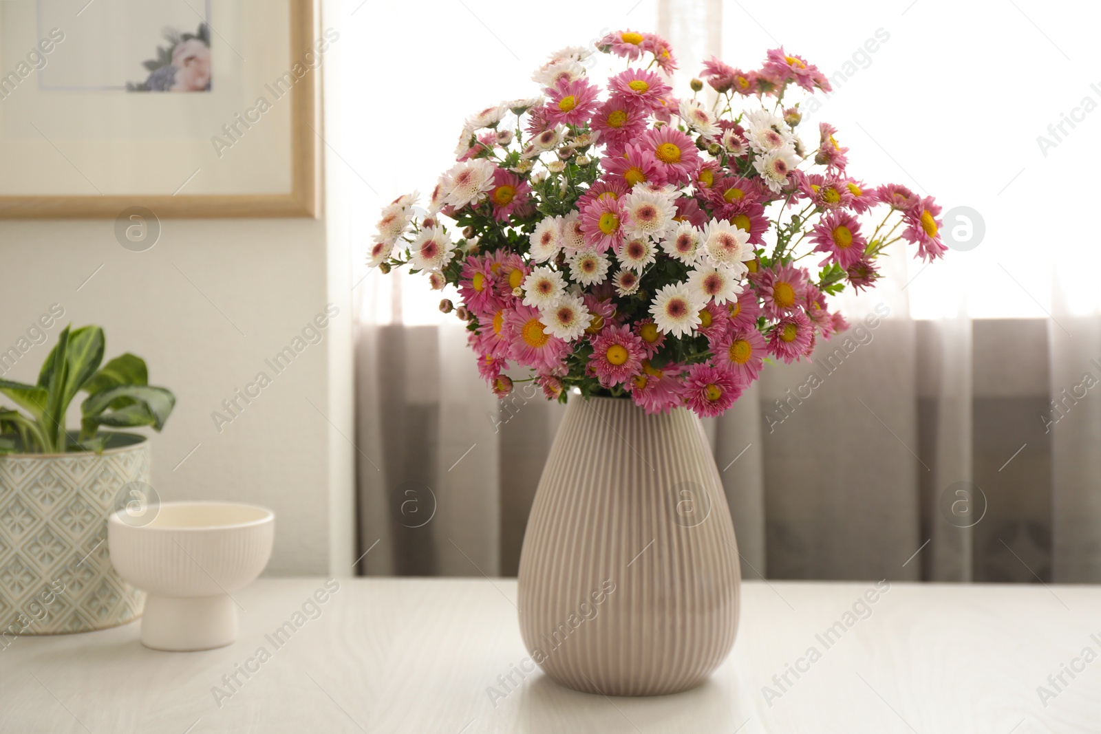 Photo of Beautiful flowers in vase and decor on white wooden table at home