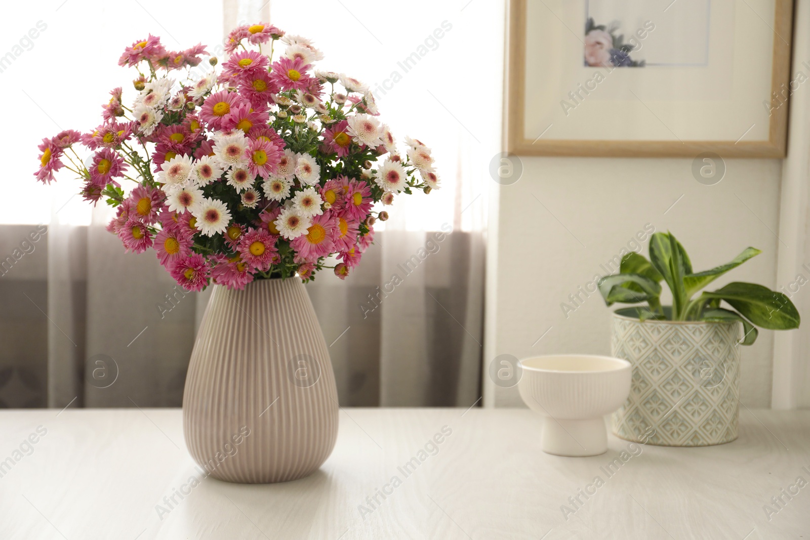 Photo of Beautiful flowers in vase and decor on white wooden table at home