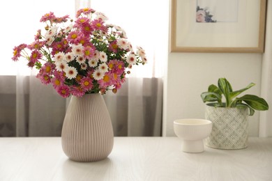 Photo of Beautiful flowers in vase and decor on white wooden table at home