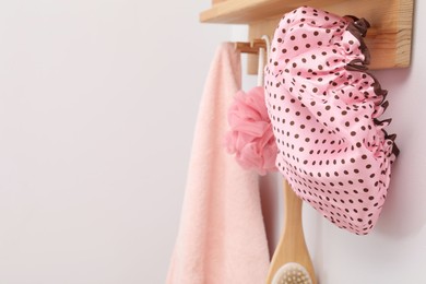 Photo of Shower cap, brush, mesh sponge and towel on rack indoors, space for text