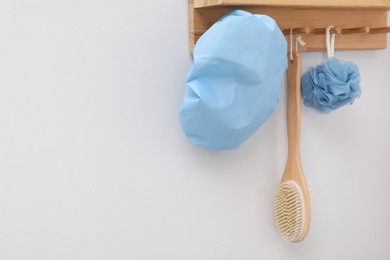 Photo of Shower cap, brush and mesh sponge on rack indoors, space for text