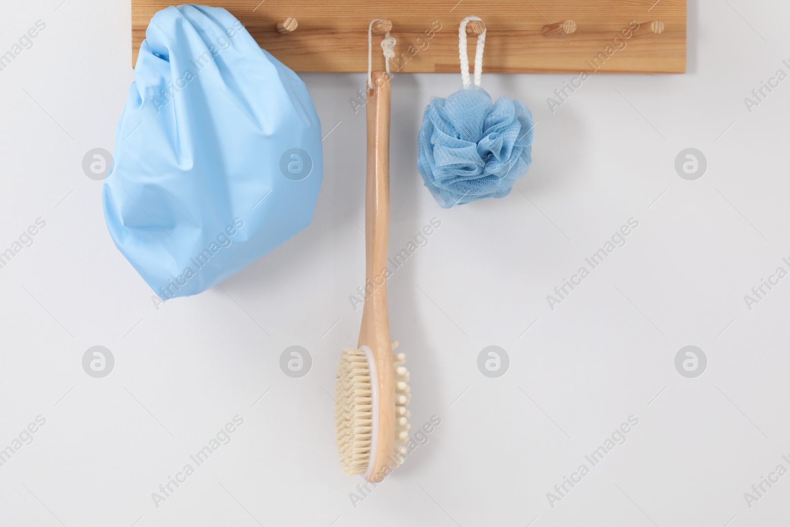 Photo of Shower cap, brush and mesh sponge on rack indoors