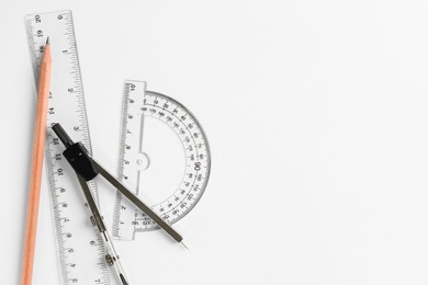 Photo of Rulers, pencil and compass on white background, flat lay. Space for text