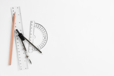 Photo of Rulers, pencil and compass on white background, flat lay. Space for text