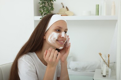 Photo of Teenage girl with cleansing foam on her face at home. Acne treatment