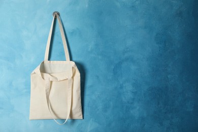 Photo of Eco bag hanging on light blue wall. Mockup for design