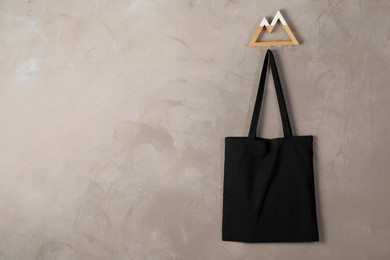 Photo of Black eco bag hanging on grey wall. Mockup for design