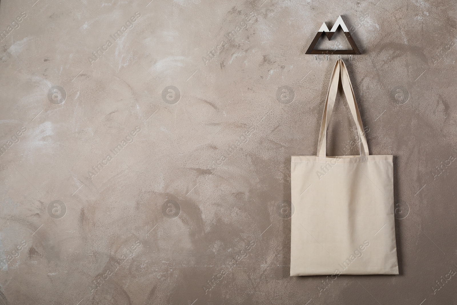 Photo of Eco bag hanging on grey wall. Mockup for design