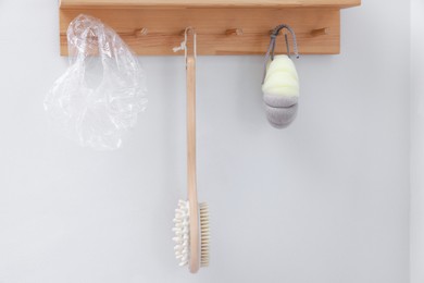 Photo of Shower cap, brush and mesh sponge on rack indoors