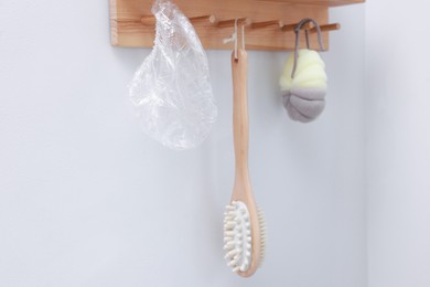 Photo of Shower cap, brush and mesh sponge on rack indoors