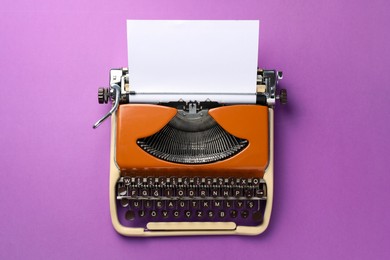 Photo of Vintage typewriter with sheet of paper on purple background, top view