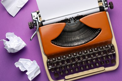 Photo of Vintage typewriter with sheet and crumpled paper on purple background, top view