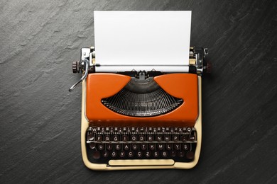 Photo of Vintage typewriter with sheet of paper on black background, top view