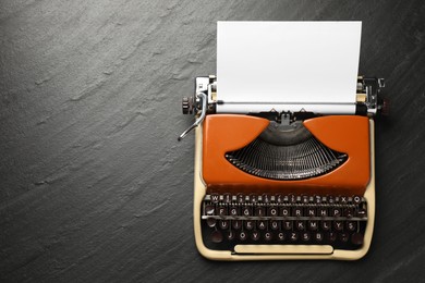 Photo of Vintage typewriter with sheet of paper on black background, top view. Space for text