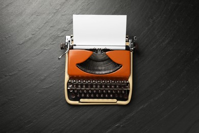 Photo of Vintage typewriter with sheet of paper on black background, top view
