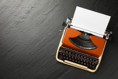Photo of Vintage typewriter with sheet of paper on black background, top view. Space for text