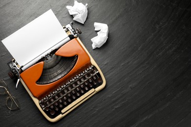 Photo of Vintage typewriter with sheet and crumpled paper on black background, top view. Space for text