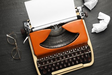 Photo of Vintage typewriter with sheet and crumpled paper on black background, top view