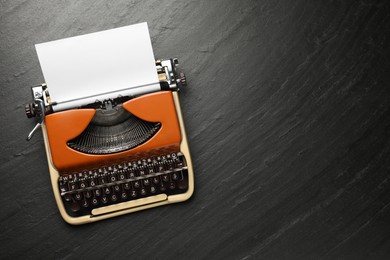 Photo of Vintage typewriter with sheet of paper on black background, top view. Space for text