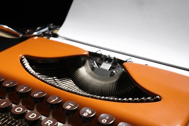 Photo of Vintage typewriter with sheet of paper on black background, closeup