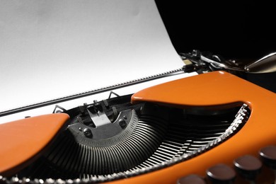 Photo of Vintage typewriter with sheet of paper on black background, closeup