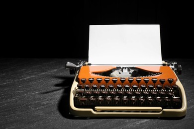 Photo of Vintage typewriter with sheet of paper on black background. Space for text