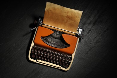 Photo of Vintage typewriter with parchment paper on black background, top view