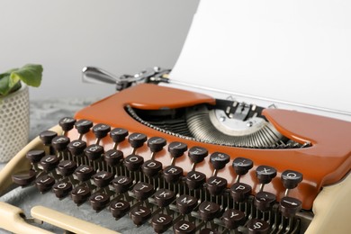 Photo of Vintage typewriter with sheet of paper on grey table, closeup