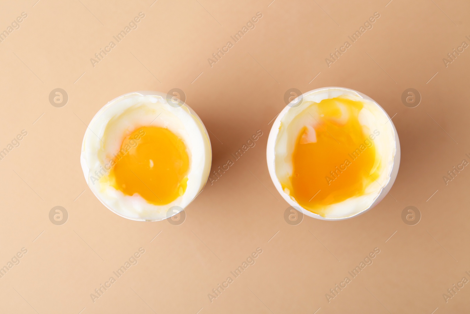 Photo of Soft boiled eggs in cups on beige background, top view