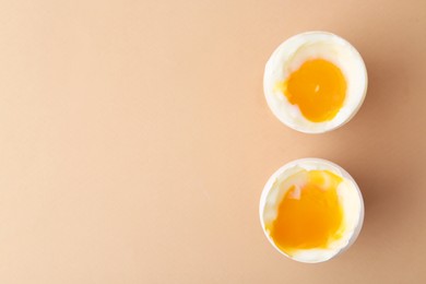 Photo of Soft boiled eggs in cups on beige background, top view. Space for text