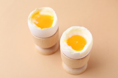 Photo of Soft boiled eggs in cups on beige background, closeup