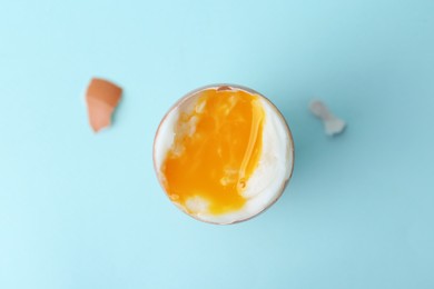 Photo of Soft boiled egg in eggcup on light blue background, top view