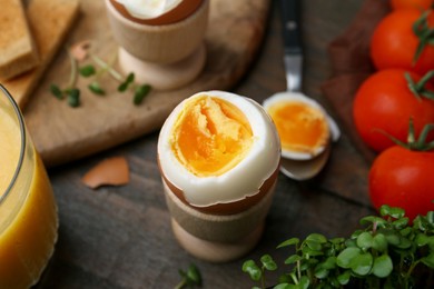 Photo of Soft boiled egg, microgreens and tomatoes on wooden table, closeup