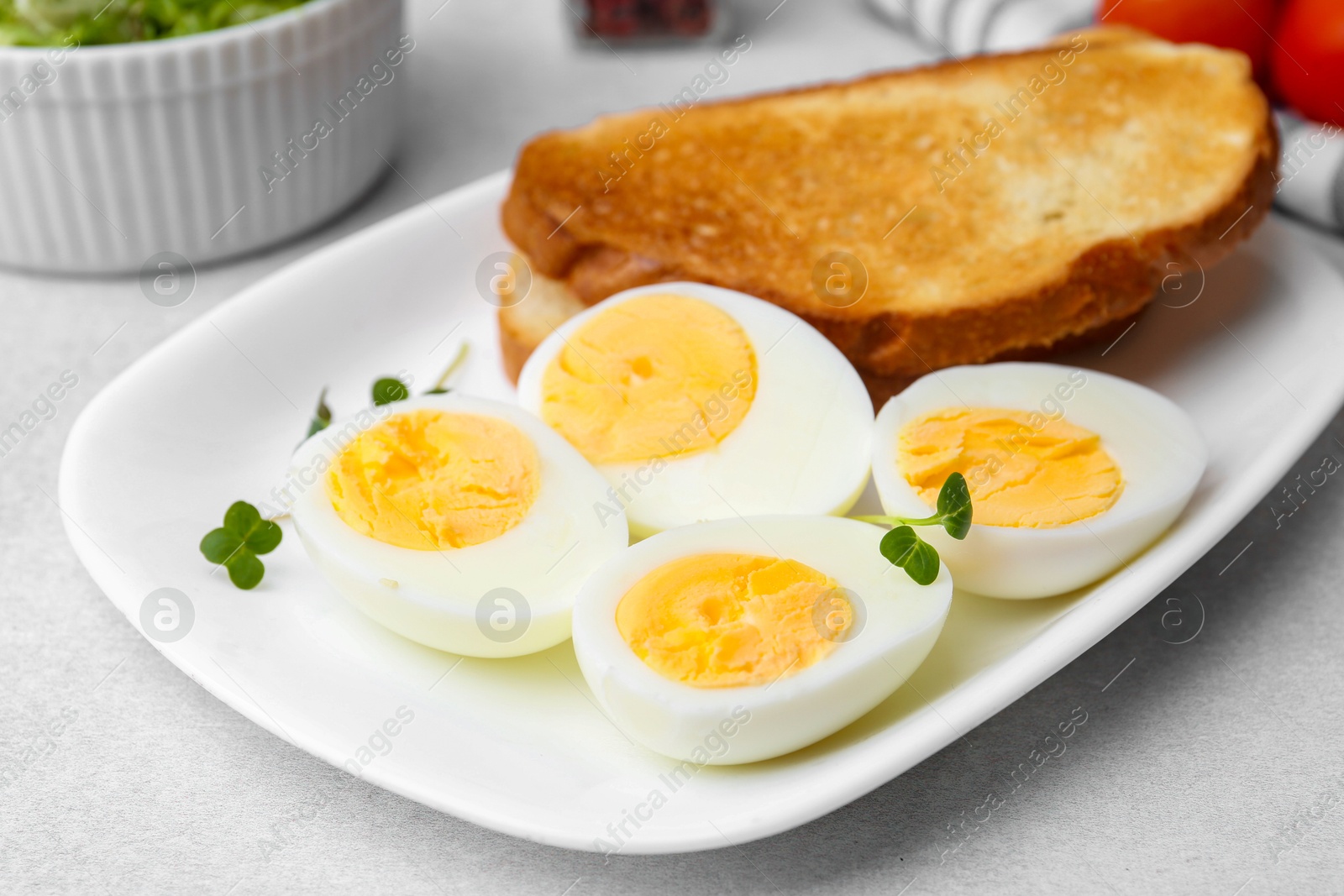 Photo of Hard boiled eggs with bread on light table, closeup