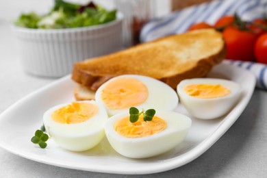 Photo of Hard boiled eggs with bread on light table, closeup